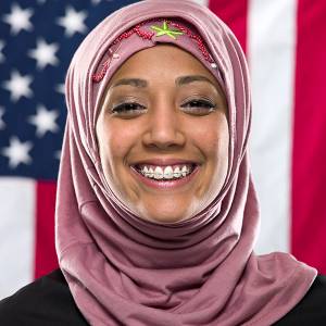 Photo of smiling muslim woman in front of U.S. flag.