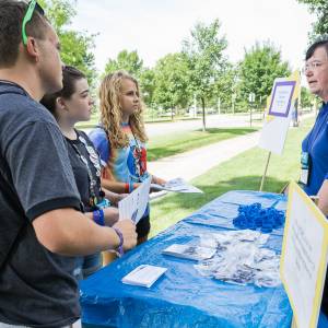 Students from Peaks and Prairies and Chicago presbyteries, Eli, Abby and Hannah, speak with Beth Snyder of Presbyterian Disaster Assistance during the Triennium advocacy walk. (Photo by Gregg Brekke)