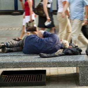 Homeless man sleeps on a city bench