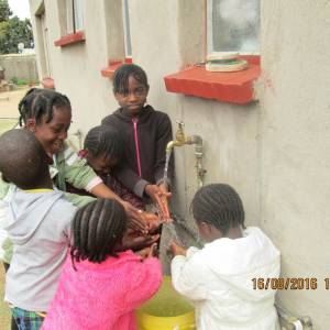 Children gather water at one of the school’s taps. (Photo by Talkmore Chilanga)