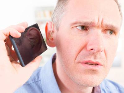 Man with a hearing disability struggles to make out the audio of a church session on his mobile phone.