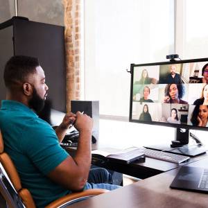 Photo of man at his desk using his computer for a Zoom conference call