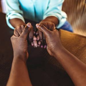 Two people holding hands in prayer