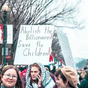 Protesters carrying sign that reads, "Abolish the billionaires! Save the children!"