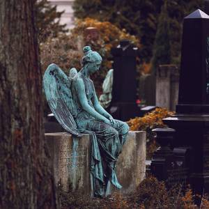 Photo of a cemetery headstone with a large angel on top Caption