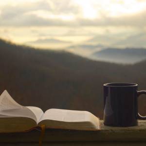 A view of the mountains in the background with a Bible and a coffee mug.