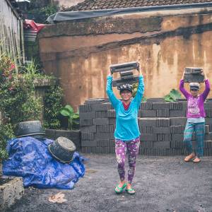 Two women carrying cinder blocks.