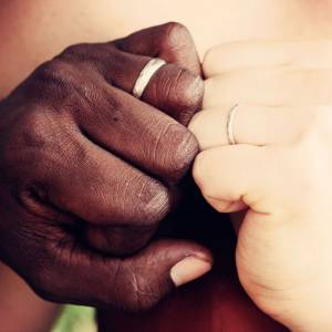 Hands of interracial couple with wedding rings