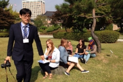 A photographer sets up a photo to include Young Adult Volunteers and students of several nationalities to promote a Korean language contest. Photo credit: Alyson Kung