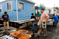 Guillermo López-Acosta(left), the Rev. Sam Weddington (second from right) and volunteers work to hoist a trailer in the Metropolitan Mobile Home Park in Moonachie, New Jersey.