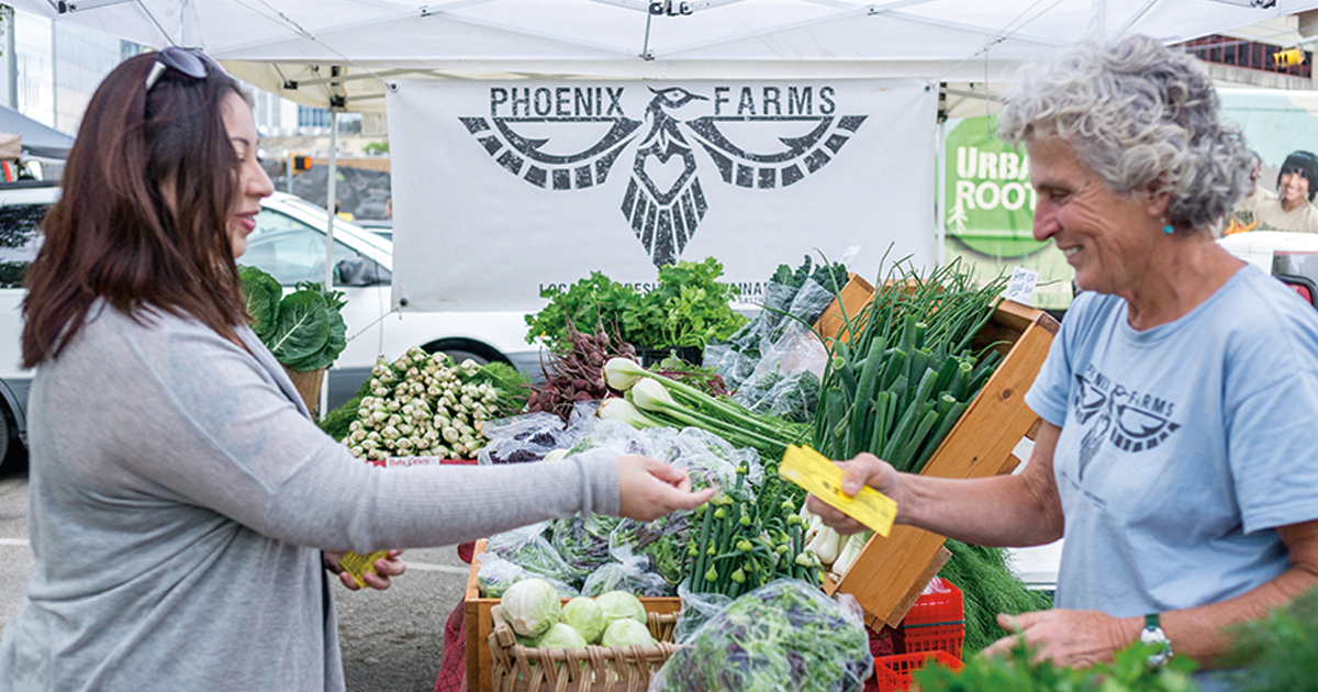 women at farmers market taking voucher