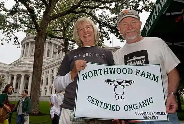 Jim and wife holding dairy farm sign